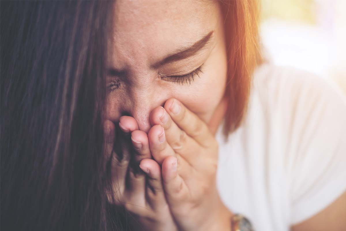 woman breathing into her hands to avoid causes of bad breath