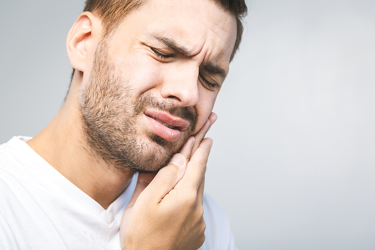 man whose jaw is in pain experiencing common dental problems