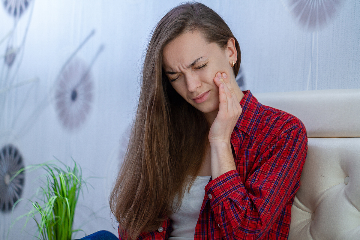 I have a dental emergency thinks woman holding jaw in pain