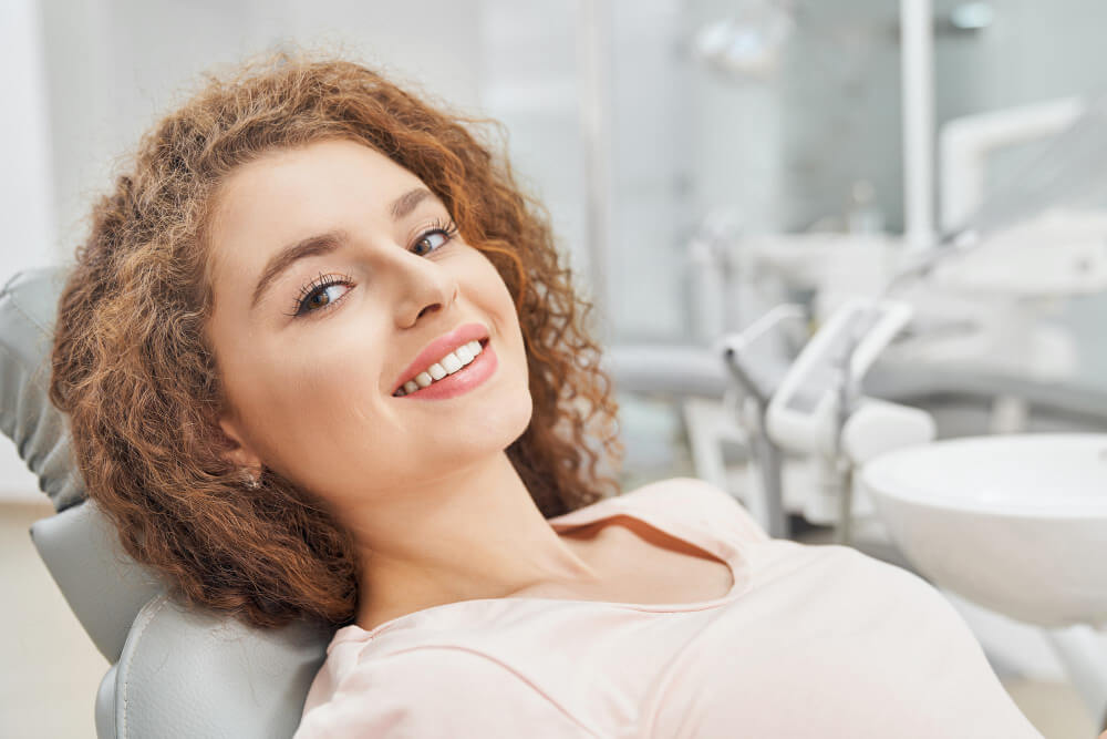 a woman smiling while laying on the dentist chair