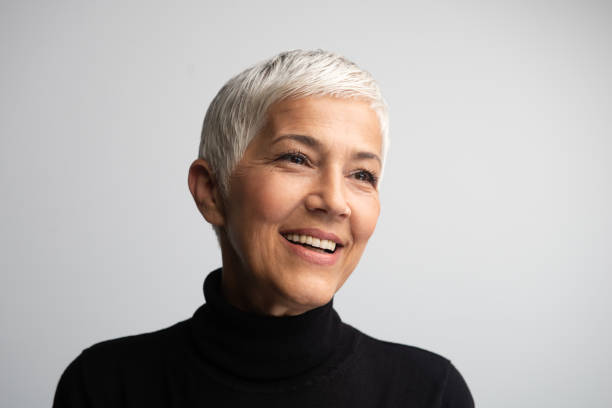 a woman wearing a black turtle neck with short white hair, smiling