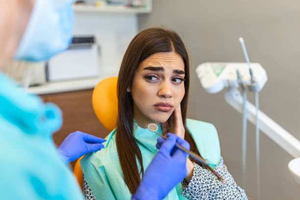 a woman sitting on a dental chair with a tooth ache