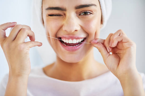 a woman with beautiful teeth smiling while flossing
