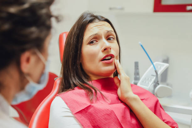 a woman touching her jaw as she talks with a dentist