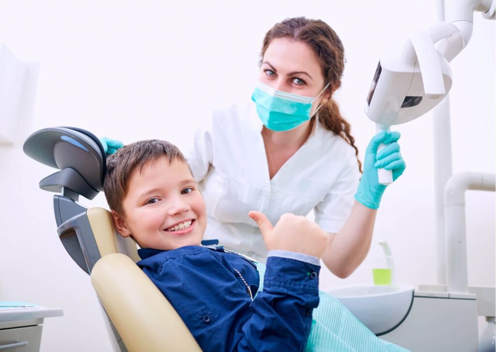 Child smiling in a dental chair during a pediatric dental visit, highlighting how a dental spacer for kids helps maintain proper spacing for incoming permanent teeth.