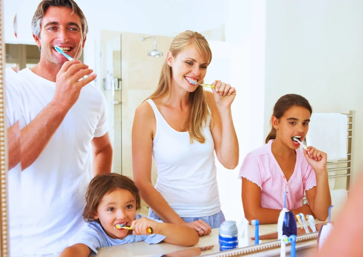 Family brushing their teeth together as part of a daily cavity prevention routine.