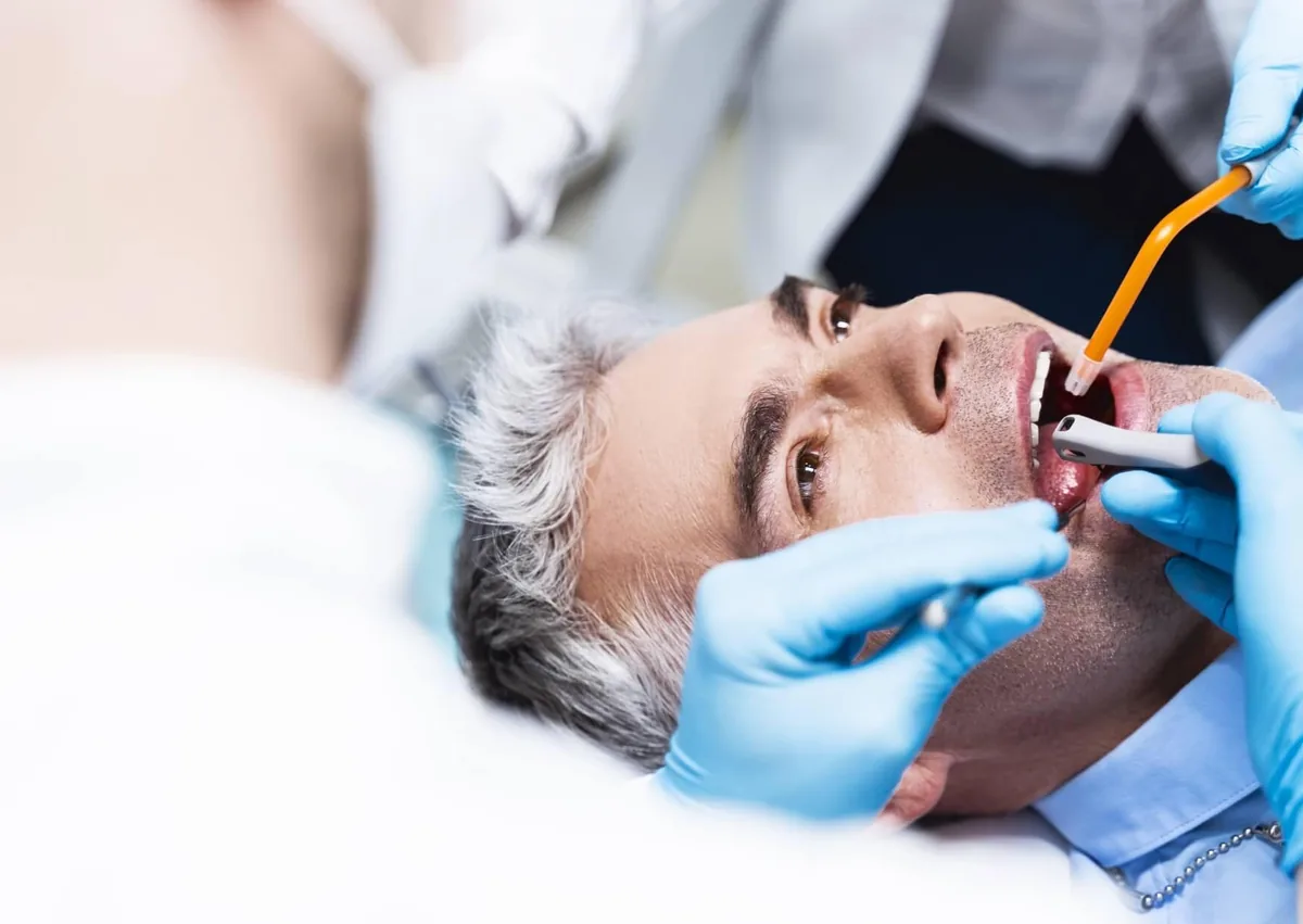 Dentist examining a patient’s tooth while evaluating whether a root canal or extraction is needed.