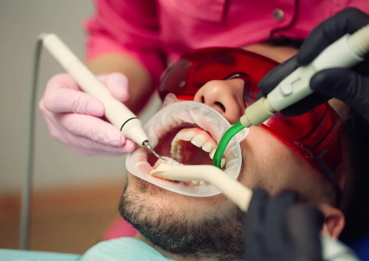 Dental professional performing a routine dental cleaning on a patient using professional cleaning instruments.
