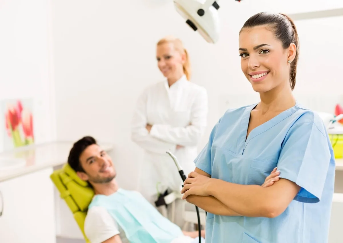 Dental hygienist with a patient in a dental chair during a routine dental cleaning appointment.