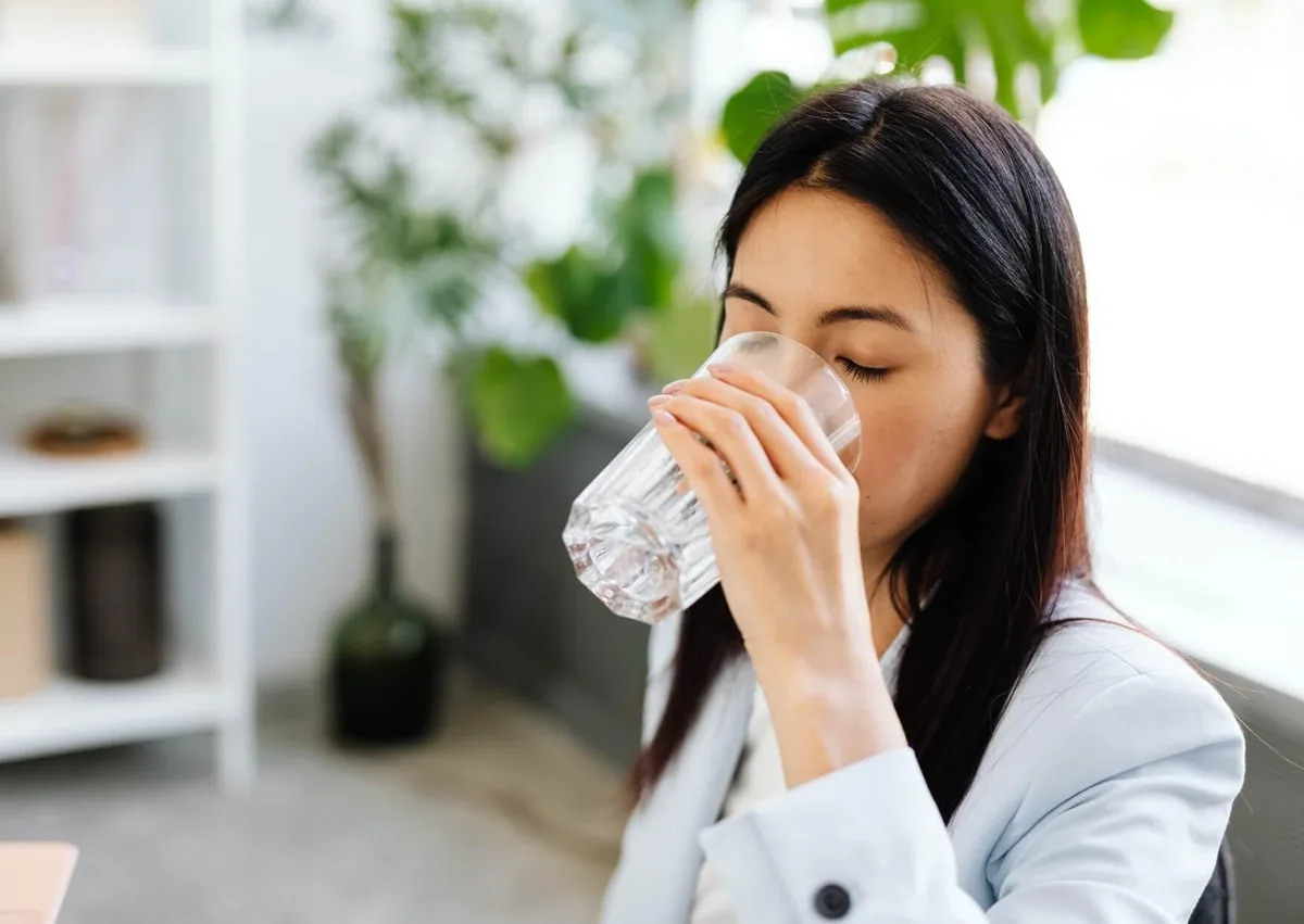 Woman drinking water to relieve symptoms of persistent dry mouth.